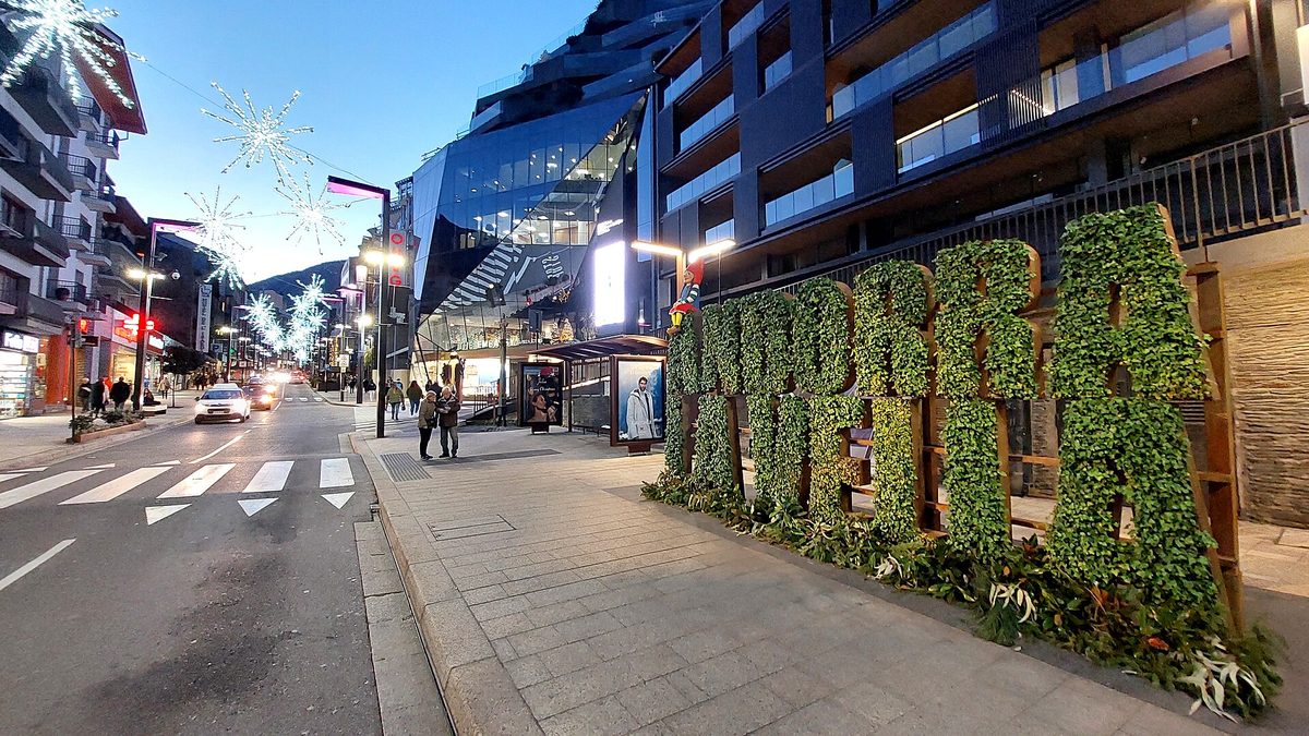 The shopping avenues of Andorra la Vella lit at dusk, with the ANDORRA garden lettering