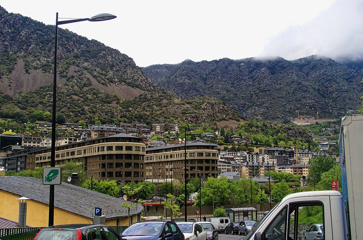 Andorra la Vella townscape with curved modern apartment blocks and parked cars below steep green Pyrenean mountainsides
