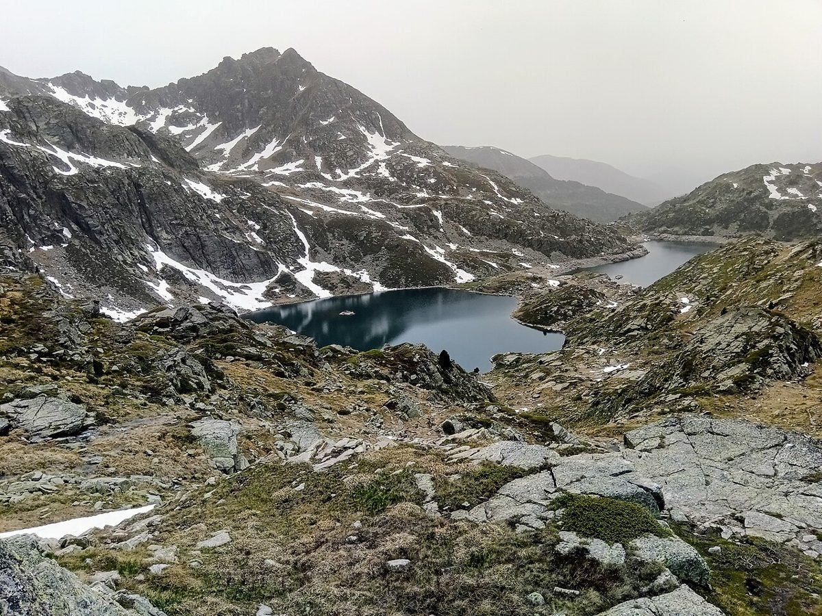The Juclar lakes in Andorra seen from the Collada de Juclar, dark water below rocky ridges streaked with late-lying snow