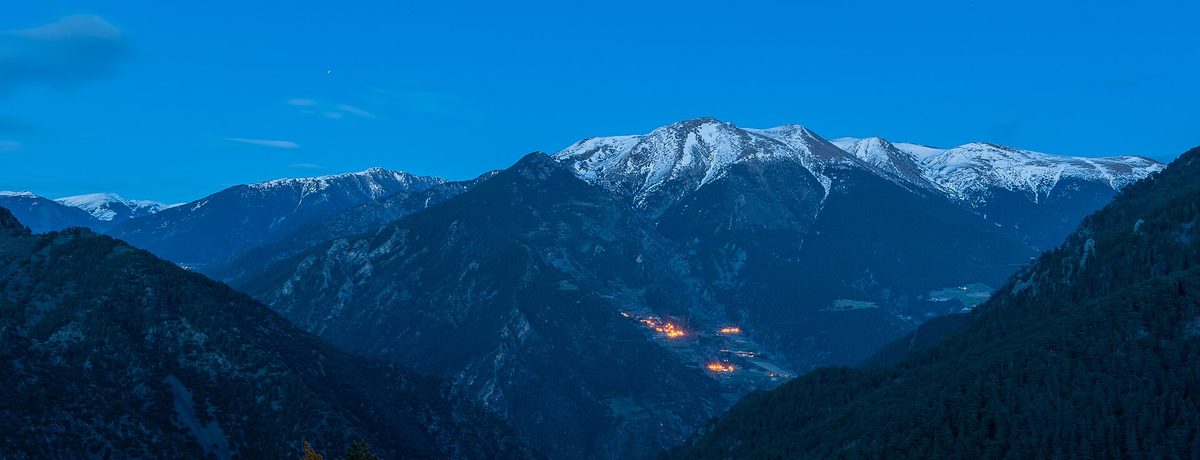 Snow-covered Pyrenean peaks above an Andorran valley at dusk