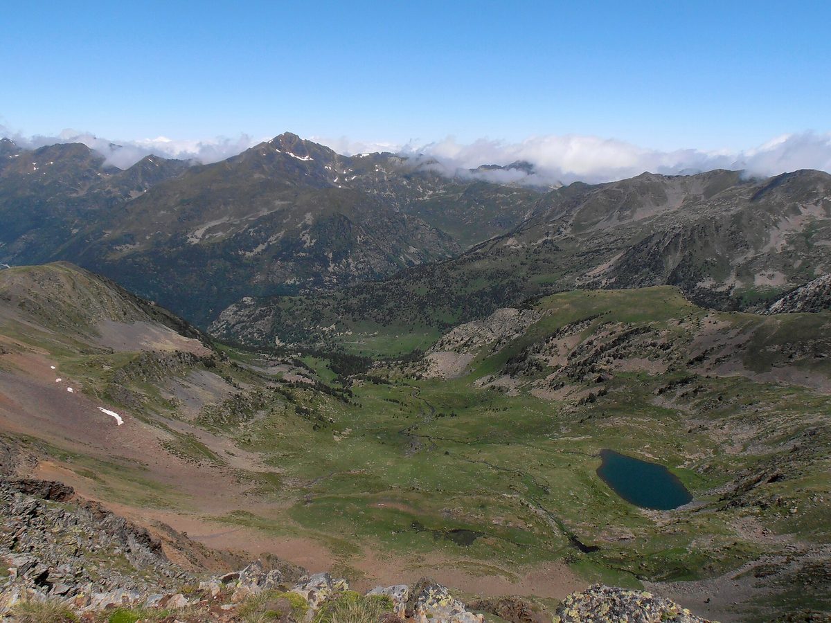 High view over Sorteny Valley Natural Park, Andorra, with the alpine lake Estany de l'Estanyo in its grassy basin